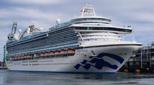 The Ruby Princess cruise ship docked at port, showing its signature blue bow artwork and multiple passenger decks.