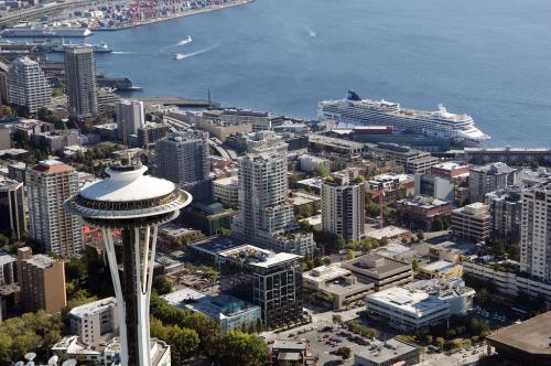 An aerial view of Seattle's Space Needle and downtown skyline with a cruise ship docked along the waterfront.