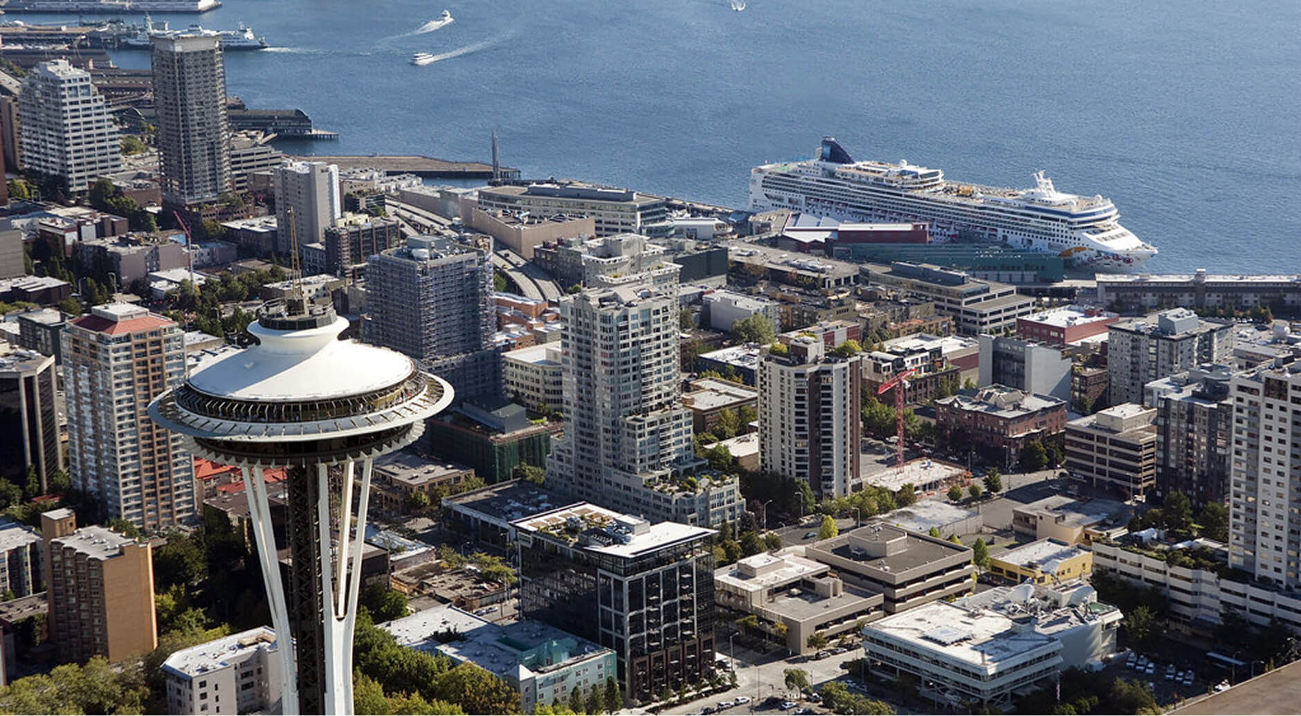 Aerial view of the Seattle Space Needle, downtown skyline, and a cruise ship docked at the waterfront terminal